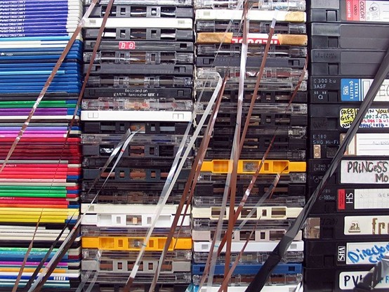 Patron economy: photograph of a stack of "old" media: floppy disks, cassette tapes, VHS tapes. Image attribution: Flickr user fernando