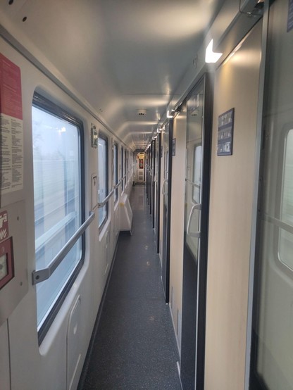 Hallway of international train. To the left, windows to the outside; to the right doors that can one can open to enter cabins.