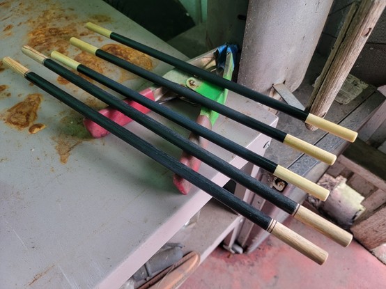 Five wooden dowels, painted black for most of their length, with tips left natural wood color and clear coated. It's a Magician's prop, used to deceive and befuddled people who too easily believe the evidence their eyes show them.
