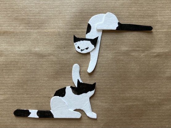 illustratie: 2 katten van wit karton die met elkaar vechten. achtergrond bruin pakpapier