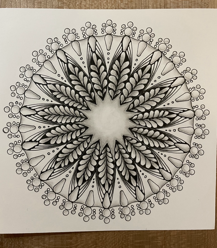 Mandala drawing with dots and pearl drops around the outside, leaf shapes in the middle, shaded with pencil 