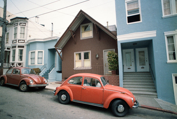A two story A-Frame with a couple of VW Bugs in front. 