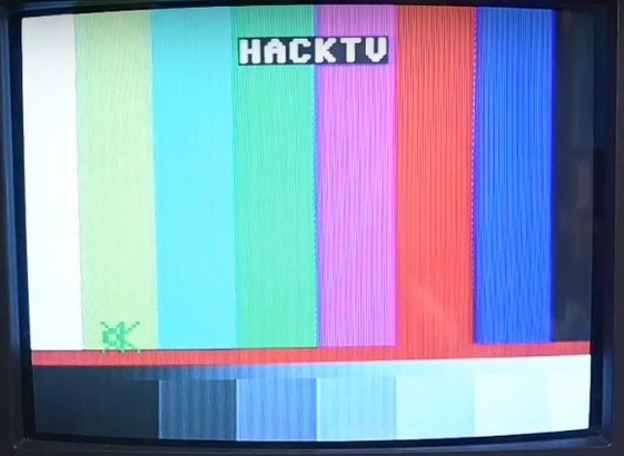 The hacktv test image displayed on a CRT television. There is a vertical banding pattern across the whole image, but mostly visible in the grey area at the bottom.