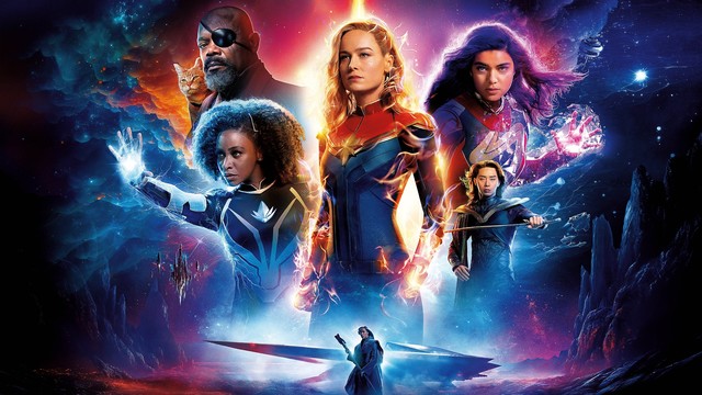 Das Trio Teyonah Parris, Brie Larson und Iman  Vellani stehen in ihren Superheldinnenuniformen kampfbereit da, umgeben von "Energie". Im Hintergrund thront Samuel L. Jackson mit einer Katze auf der Schulter im Himmel.