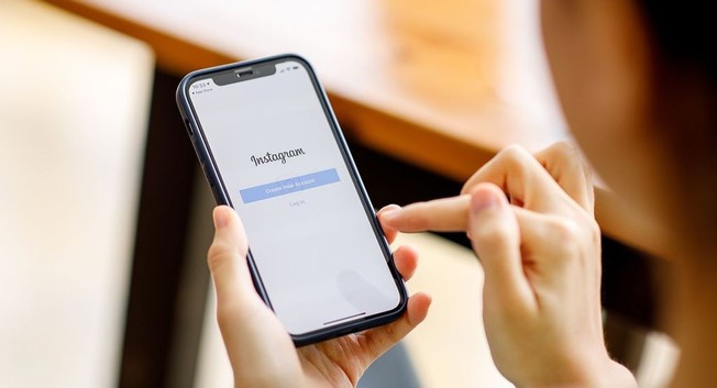 stock image of woman holding a smart phone with Instagram login on screen (IMAGE: ADOBE)