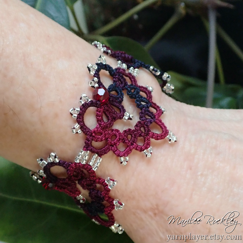 Heart design handmade lace with beads for a bracelet modeled on a wrist.