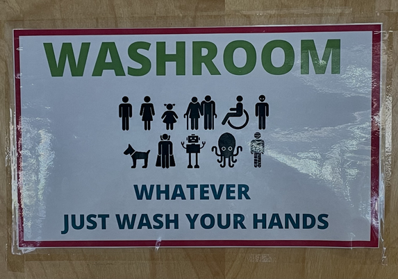 Sign in washroom door with different human, animal, and robot icons that reads:Washroom above icons and below icons, reads Whatever. Just wash your hands.