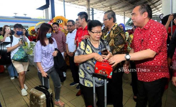 Transport Minister giving Chinese New Year goodies to passengers exiting a train. / Photo from article linked.