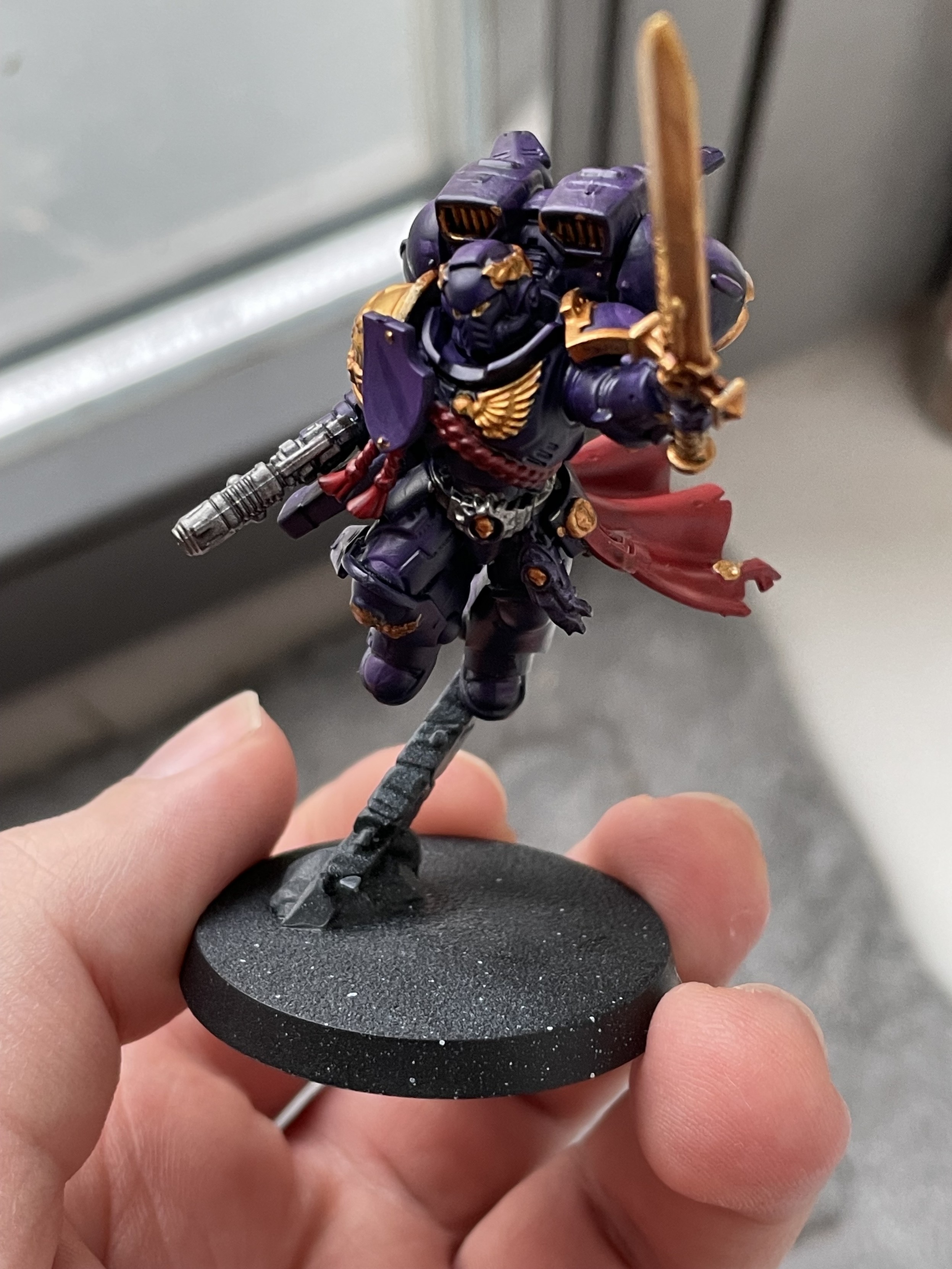 A Space Marine Captain with Jumping Rack painted in purple, red, and gold. Front view. 