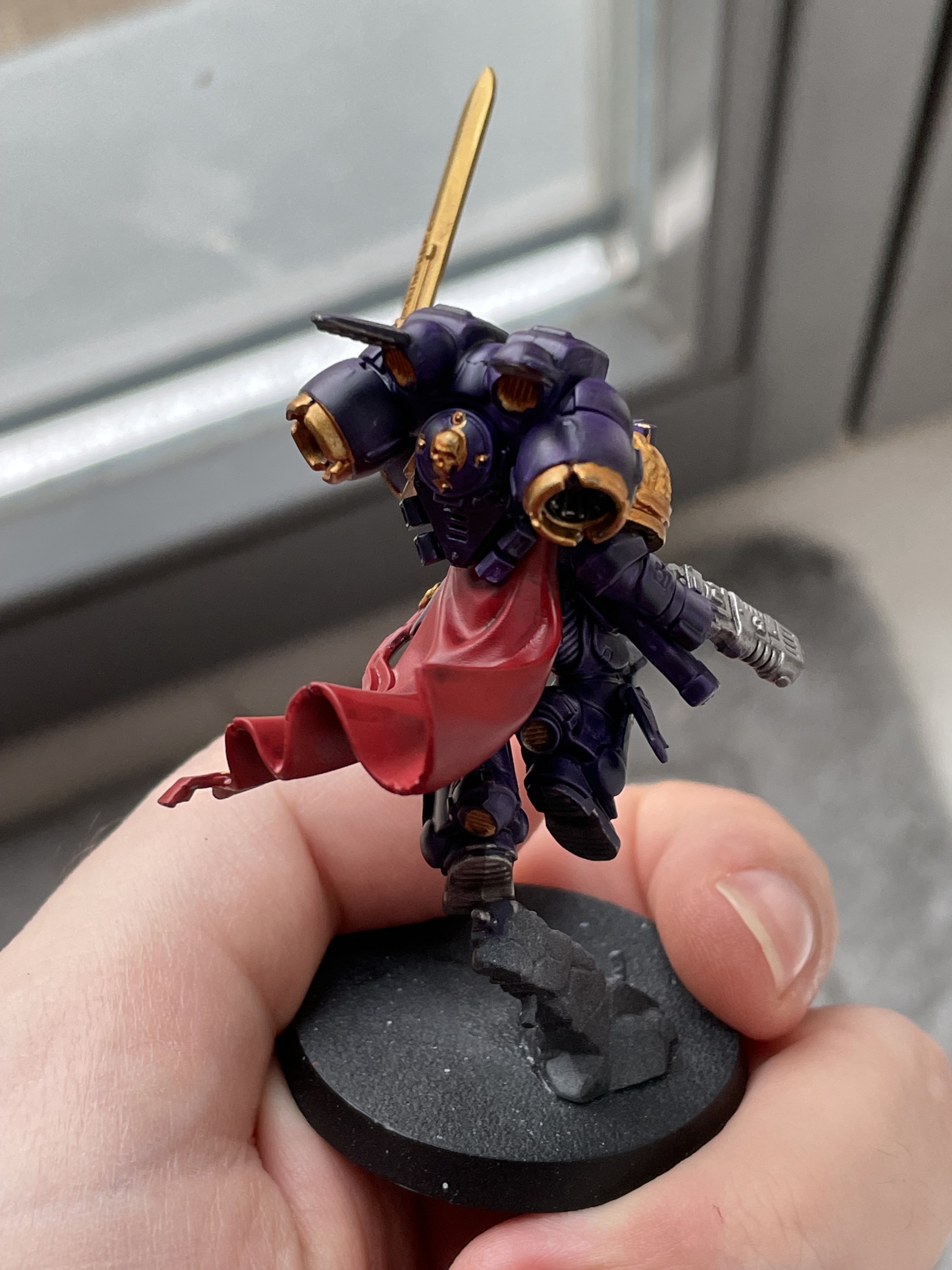 A Space Marine Captain with Jumping Rack painted in purple, red, and gold. Back view.