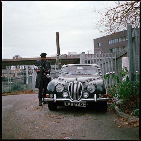 Photo of a photographer standing near a vintage car.