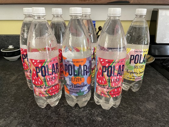 8 one liter Polar seltzer plastic bottles on a kitchen counter. Each if filled to the top with maple sap.