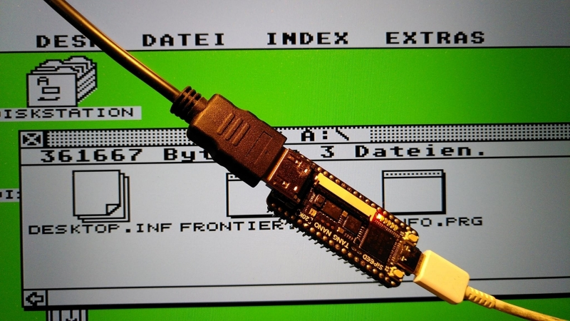 Ein FPGA-Board auf dem ein Atari-ST Core läuft. Im Hintergrund ist ein Screenshot vom Atari Desktop zu sehen