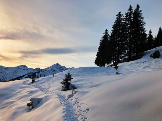 A path in the snow with some mountain peaks in the distance
