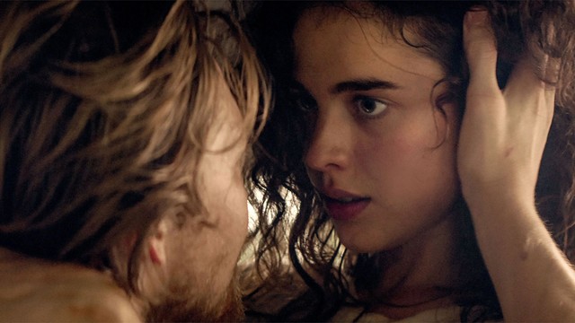 Ein Mann legt seine Hand an die rechte Schläfe von Margaret Qualley, sieht schaut ihm tief in die Augen, ihre Stirnen berühren sich fast