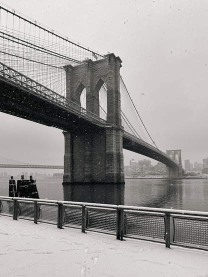Brooklyn Bridge and some falling snow. The photo is taken from the Manhattan side. Across the East River is the Brooklyn skyline. 