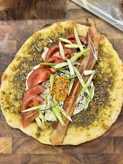 Manouche a la Samer: breakfast pizza with zaatar, olive oil, Benton’s bacon, sumac egg, tomatoes, and sliced green onions