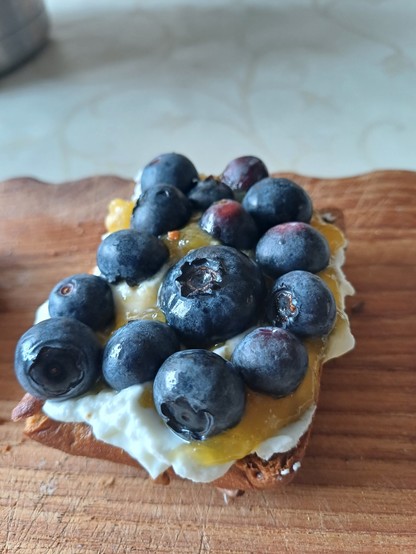My breakfast roll, cut in half and toasted, with Quark (a German fresh cheese), homemade jam, and blueberries on top. One blueberry is a monster!