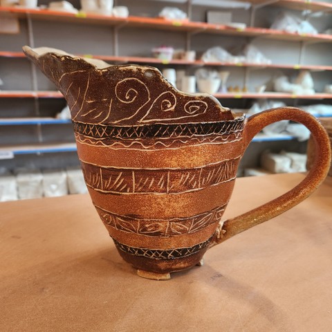 Handmade pitcher, decorated with bands of warm browns and carved decoration.