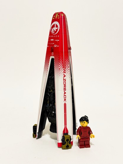 A photo of a model of the Razorback racing pinnace from the science fiction show The Expanse, with a LEGO minifigure representing the character Julie Mao standing alongside