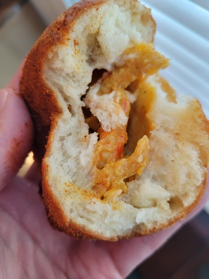 Crawfish beignet, partially eaten and showing the filling.