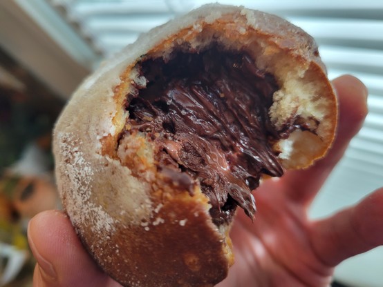 Chocolate beignet, partially eaten, showing the filling of molten Ghirardelli chocolate
