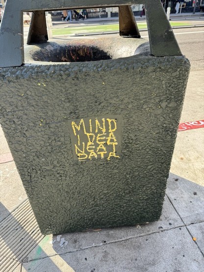 A trash can where a tagger has written the words: 
mind, idea, neat, data
