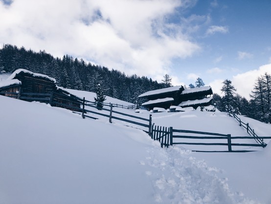 A mountain hut surrounded by a fence and overall snow