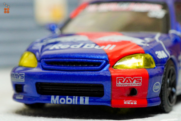 A close-up shot of Honda Civic Type-R EK9 No Good Racing Red Bull Livery by INNO64 in 1:64 scale with 1:64 figure on area 164