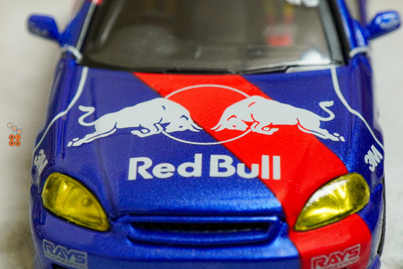 A close-up shot of Honda Civic Type-R EK9 No Good Racing Red Bull Livery by INNO64 in 1:64 scale with 1:64 figure on area 164