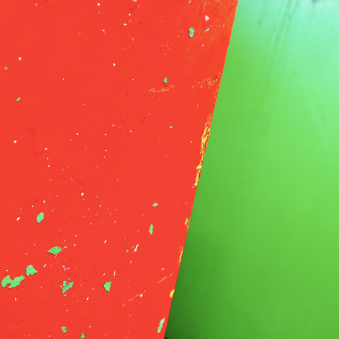 Abstract blocks of colour formed by the juxtaposition of the local recycling bins. Each metal bin is painted in a primary colour. Generally unattractive, this perspective brings a splash of colour from otherwise boring urban furniture. Here: red against green. 