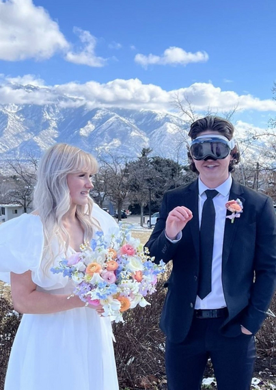 Wedding photo of a couple standing in front of beautiful, sweeping snow, sprinkled mountains, a beautiful, feme, light skinned with blonde hair, wearing a white dress and holding a beautiful bouquet of flowers, stands staring at her groom a light skinned masc with short curly hair …wearing an #AppleVisionPro for some godforsaken reason.
The brides expression definitely seems to evoke “my God, what have I done” 
But I hope it’s just a momentary accident of the picture for her sake  😂