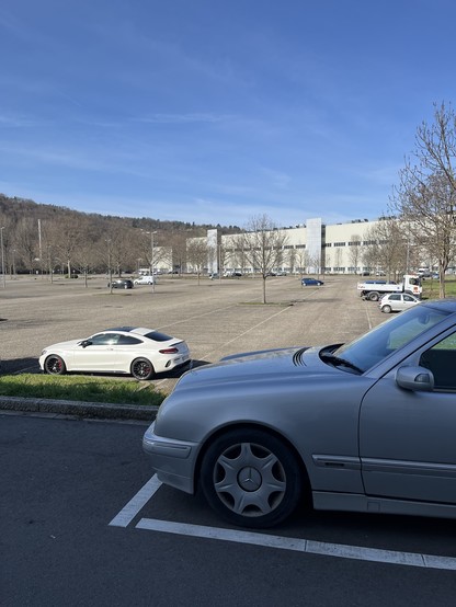 Symbolbild: zwei parkende Autos und ein am Samstag fast leerer Werksparkplatz