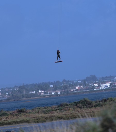 Un surfista que parece estar "volando" con su kitesurf sobre el caño de Sancti Petri, por encima del poblado que se ven al fondo de la imagen.