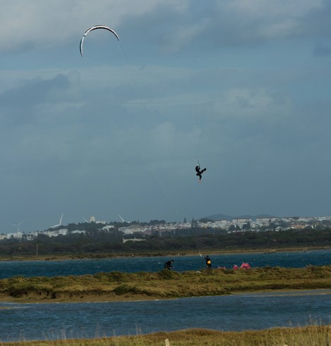 Un surfista que parece estar "volando" con su kitesurf sobre el caño de Sancti Petri, por encima del poblado  que se ven al fondo de la imagen.