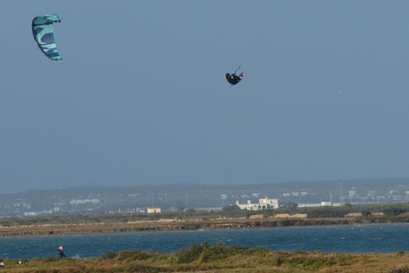 Un surfista que parece estar "volando" con su kitesurf sobre el caño de Sancti Petri, por encima del poblado que se ven al fondo de la imagen.