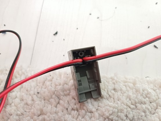 Opened LEGO rail connector with a new cable.