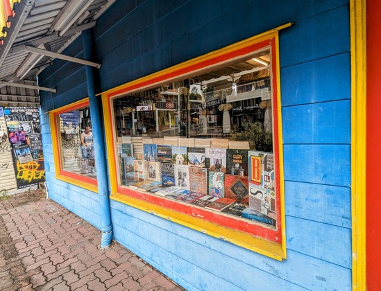 Bookshop window with many coffee table hardbacks on display.
Bright Blue wall, bright yellow and red door and window trim.