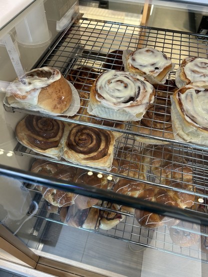 Shelves of cinnamon buns and other treats in a bakery.