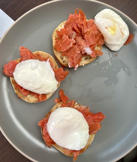 A plate with three servings of smoked salmon and poached eggs on English muffins.