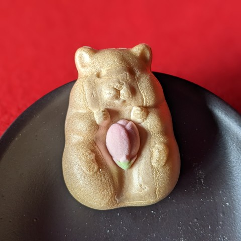 Hamster Monaka holds tightly to his sakura bud.