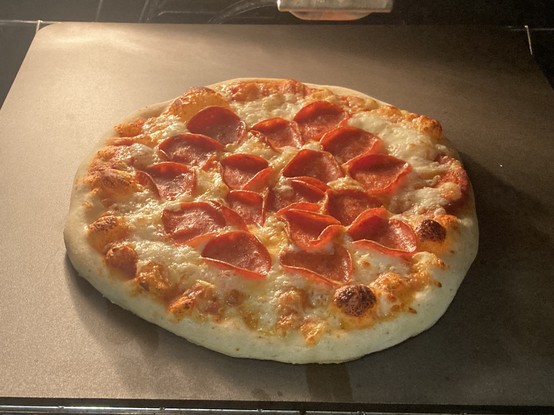 A pizza in an oven on a baking steel.