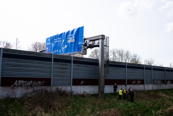 Über einer Autobahnschilderbrücke hängt ein Transparent welches Abbiegen für die Verkehrswende vorschlägt