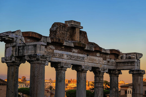 Temple of Saturn architectural details in Rome, Italy, entablature on Ionic columns at dusk against sunset sky. Ancient Roman monument dedicated to the god Saturn in 497 BC.