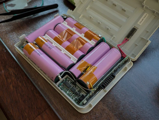 Photo of a rebuilt battery pack for the Apple iBook G3 900Mhz 14 inch version. The battery pack is still opened up, showing 8 new pink or purple-colored Samsung batteries installed, replacing the green-colored Panasonic ones that were originally installed and had started leaking (shown in the original post I am replying too)