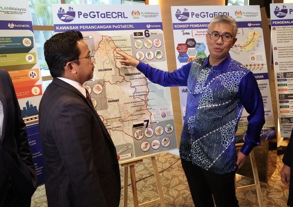 A person pointing towards a map of the ECRL alignment while talking to someone else. / Photo from linked article.