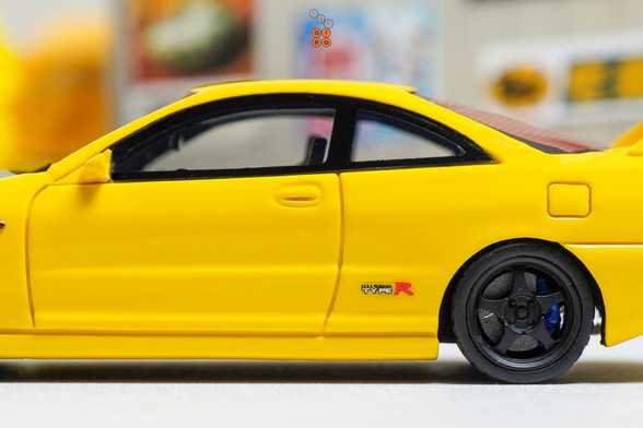 A close-up shot of yellow Honda Integra Type-R DC2 by Nice Auto in 1:64 scale with 1:64 figure on AREA 164