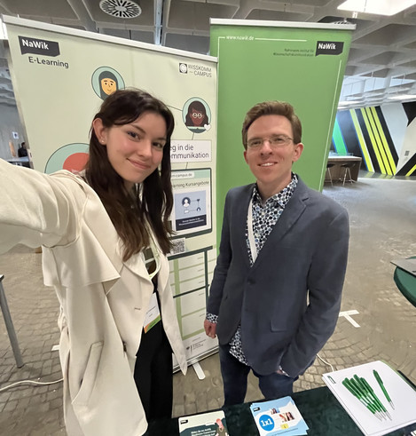 Zwei NaWik-Mitarbeitende am Stand des NaWik auf dem JCF-Frühjahrssymposium 2024 in Ulm.
