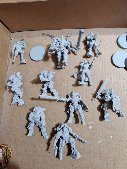Foto de las 9 miniaturas del Action Pack de la Brigada Torchlight para el juego Infinity y el Bounty Hunter exclusivo de eventos. Todas están montadas y con la capa de imprimación en color gris claro.