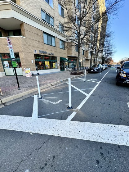 An intersection with a box crossed out that used to be a parking space. It now has flex posts to prevent drivers from being in the parking lane when turning right. 
